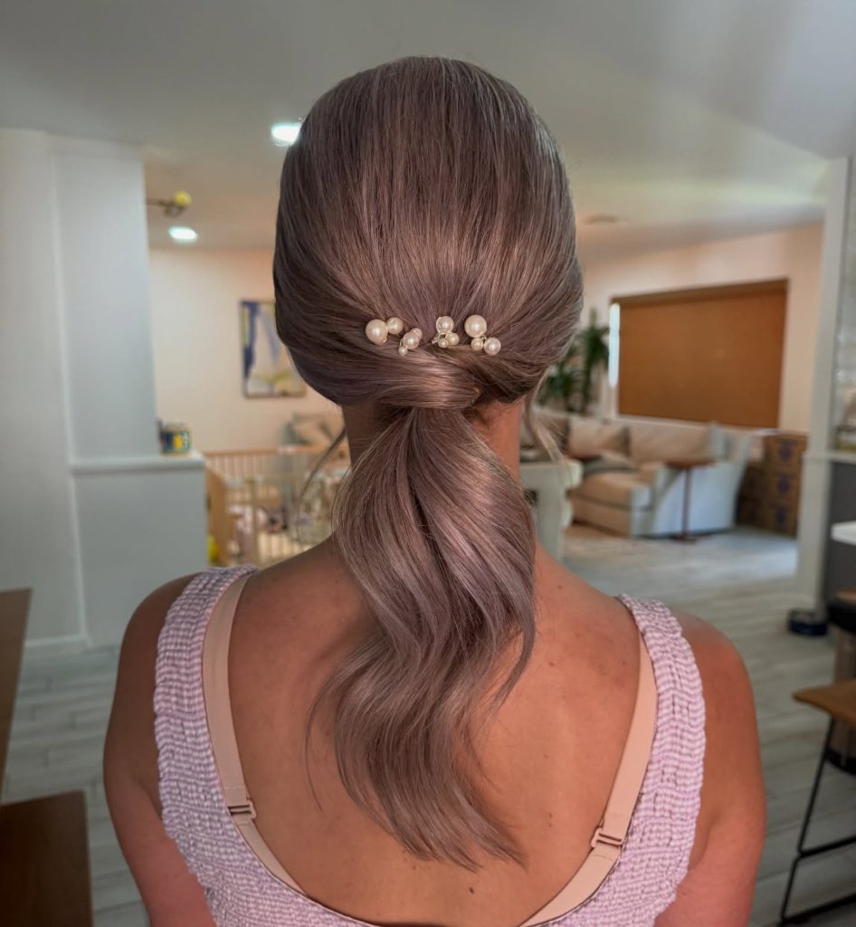 Smooth low ponytail with pearl hair accessories and soft waves