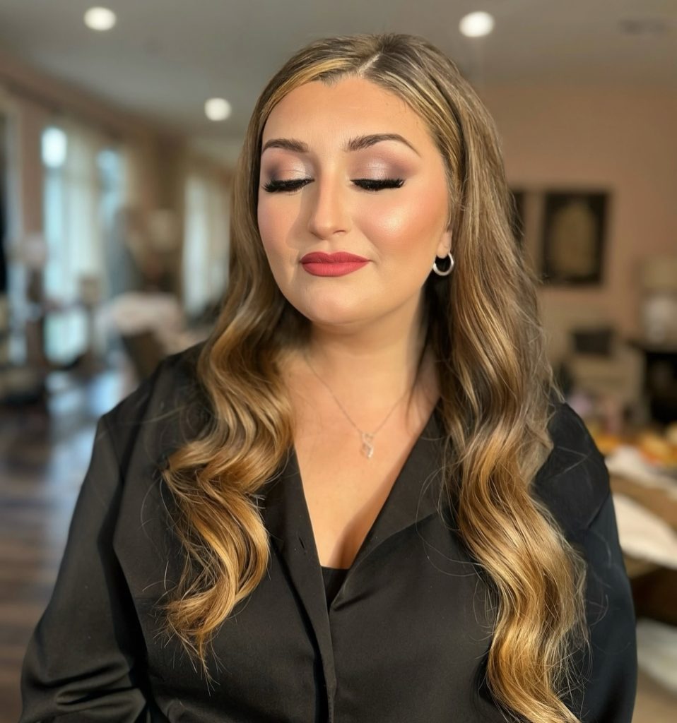 Rose-toned soft glam makeup and long highlighted waves